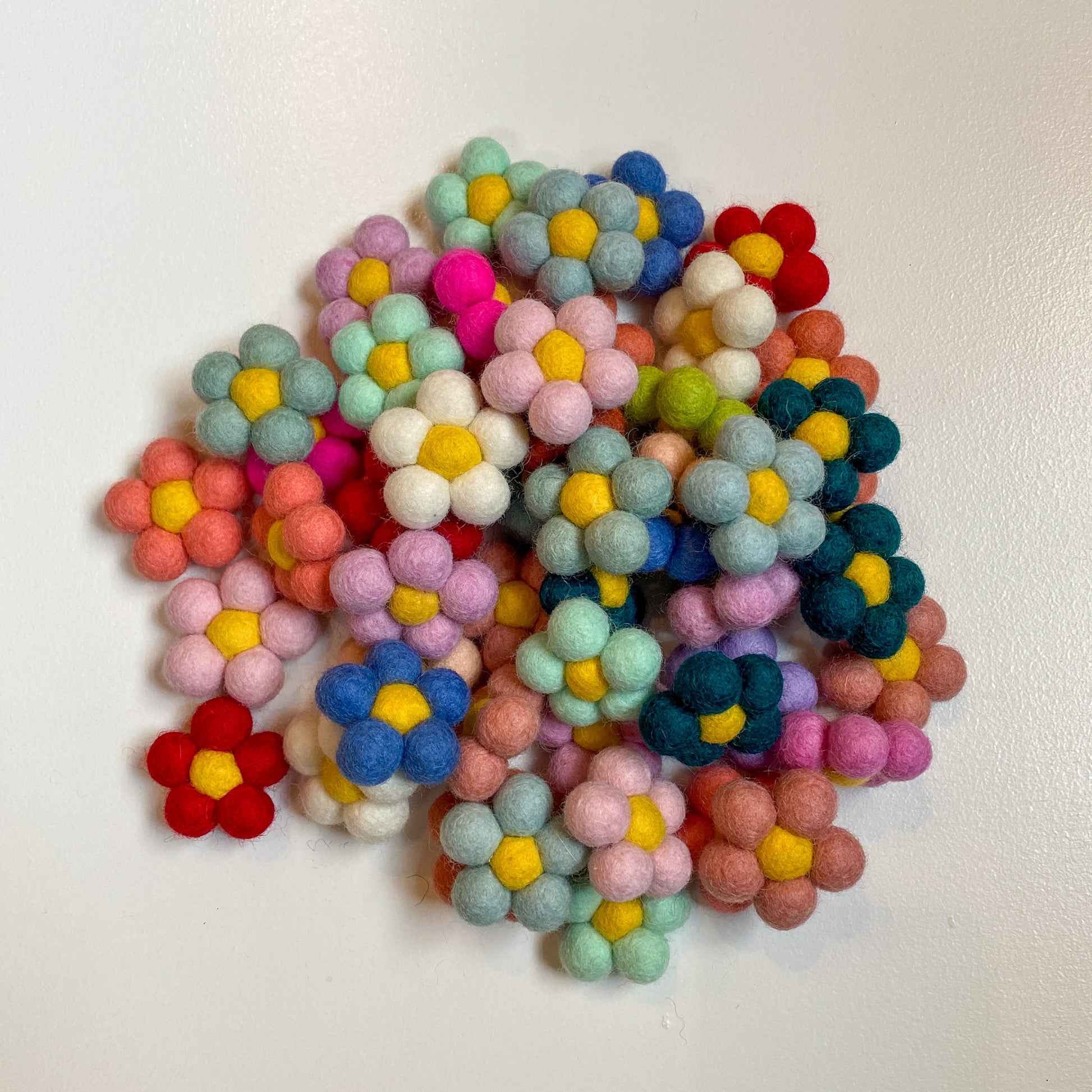 A pile of felt flowers in a variety of colors.